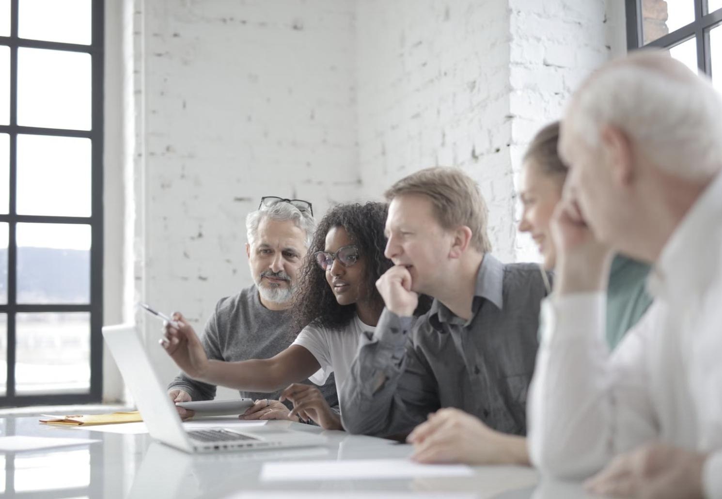 A team of real estate professionals gathered around a laptop in a meeting