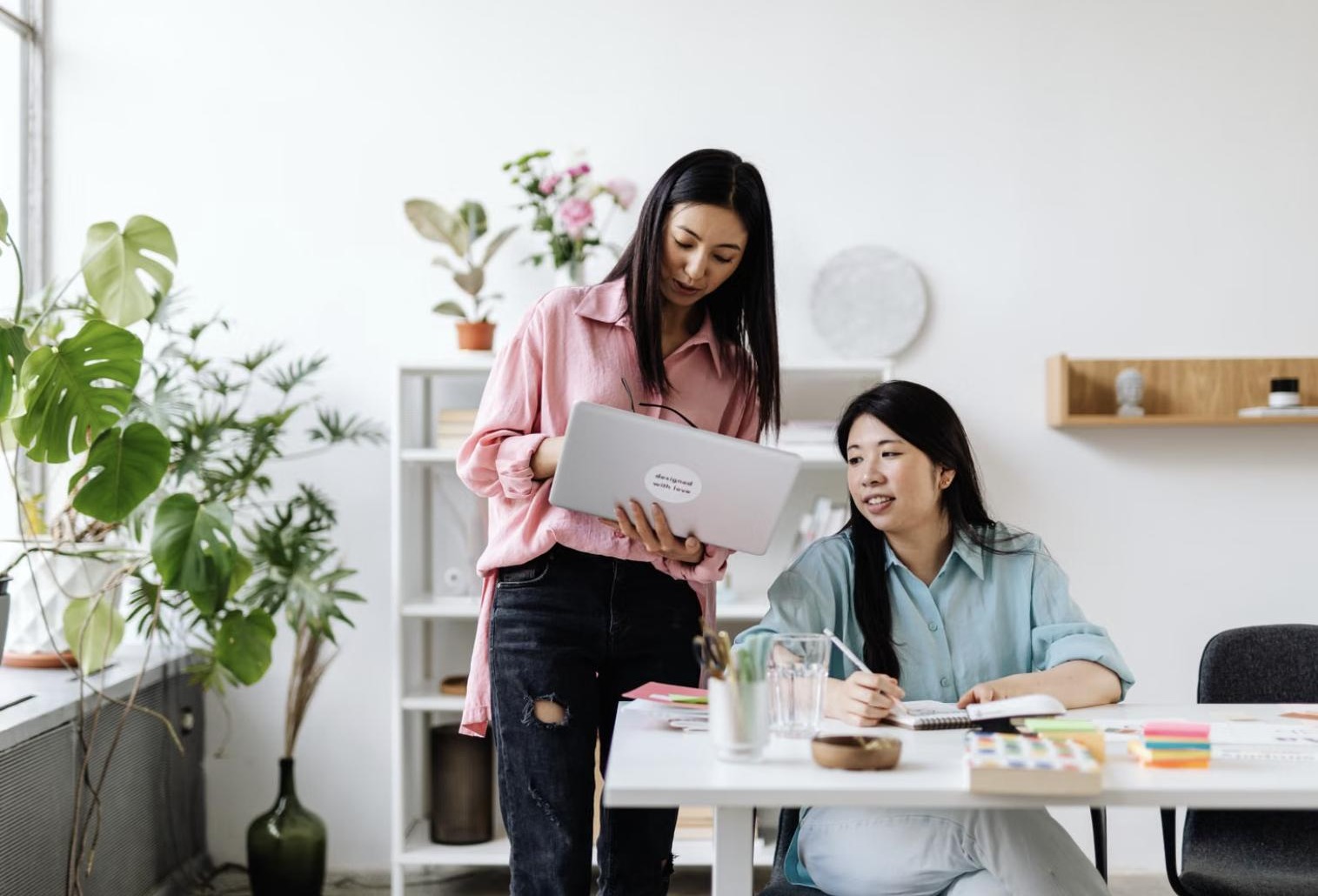 Two women reviewing documents together at a table in a bright office